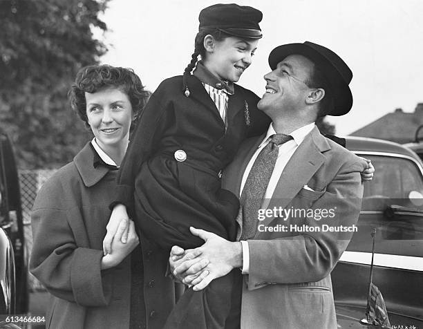 American dancer and film actor Gene Kelly visiting London with his wife, actress Betsy Blair and daughter Kerry, 1955.