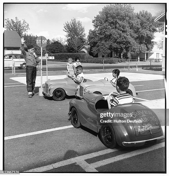 Children from the Garfield Elementary School, Arizona, drive around a course in small cars in order to learn about traffic safety.