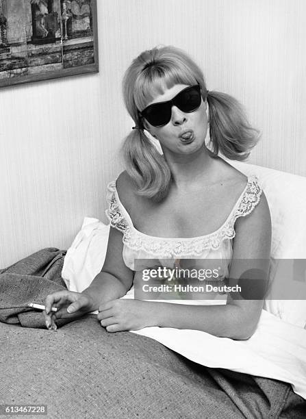 The model and show girl Mandy Rice-Davies at home in bed, 1963.