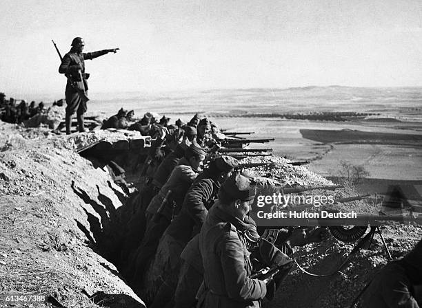 Spanish Republicans, fighting against General Franco's fascist forces, line up in a trench, guns ready for an attack, during the Spanish Civil War....
