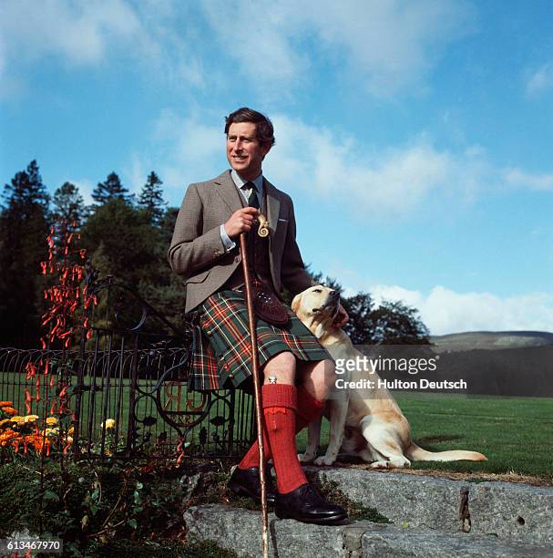 Prince Charles poses with his yellow labrador dog on the grounds of Balmoral Castle on his birthday.
