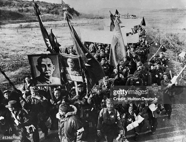 Anti-communist Chinese prisoners of the Korean War march along a road to Inchon, where they will be taken to Taiwan. They carry Chinese Nationalist...