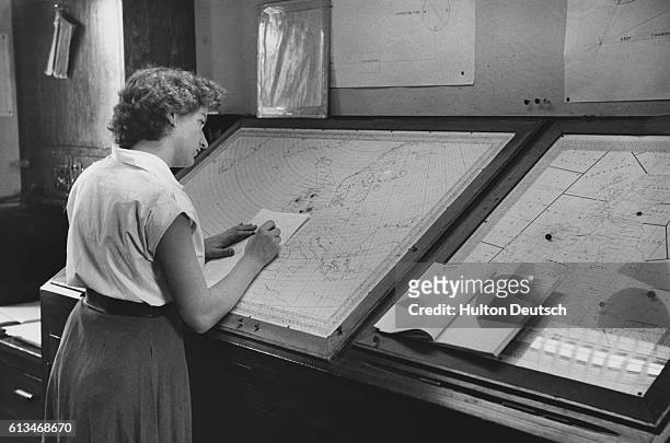 An employee at the central forecasting station of the Air Ministry Meteorological Service, uses charts to analyze the course of a thunderstorm.