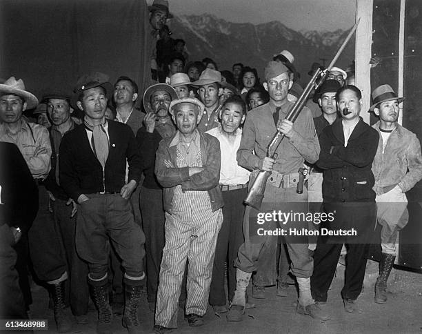 An American soldier guarding a crowd of Japanese American internees at an internment camp at Manzanar, California, USA, during World War II. |...