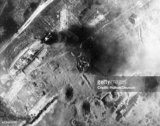 Reconnaissance aircraft flies over the remains of a workshop and truck shelter, bombed by US and South Vietnamese forces in response to a Vietcong...