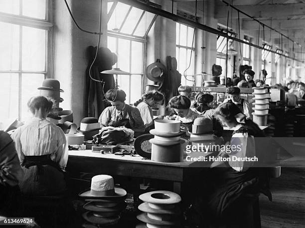 Women trim hats at the Sutton and Torkington factory in Manchester. July, 1909.