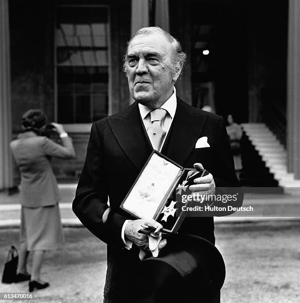 The fashion designer and Royal dressmaker Norman Hartnell outside Buckingham Palace, after reciving his knighthood from the Queen. He displays the...