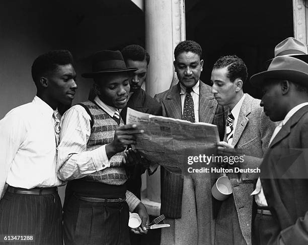 Some of the 482 Jamaicans emigrating to the UK read a newspaper on board the ex-troopship Empire Windrush which arrived at Tilbury. UK.