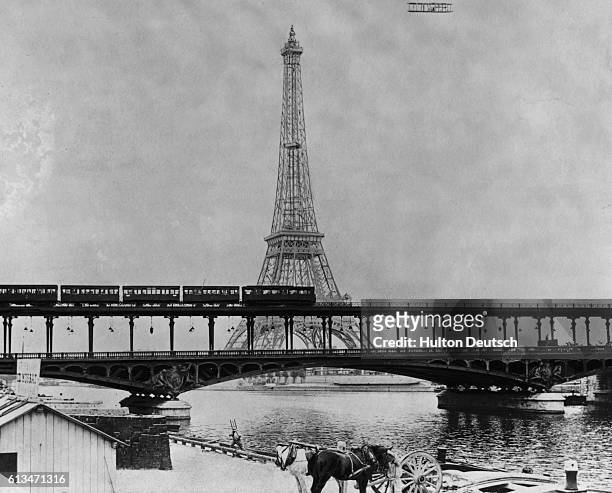 Le Comte de Lambert flies over the River Seine beside the Eiffel Tower during his 1909 round trip from Paris to Juvisy in a Wright plane.