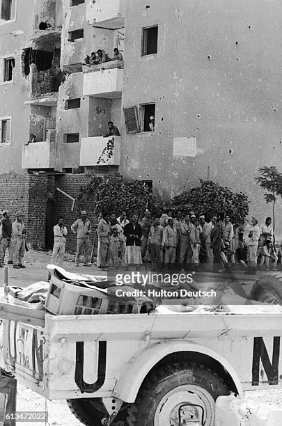 United Nations soldiers guard a settlement during the Yom Kippur War while apartment dwellers peer out of their windows.