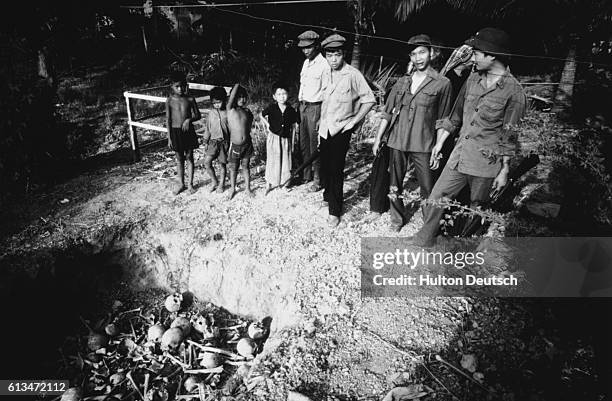 Vietnamese soldiers and a group of children witness the unearthing of a mass grave.