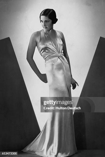 Model displays a pale, satin, halter neck dress designed in France in the mid-1930s.