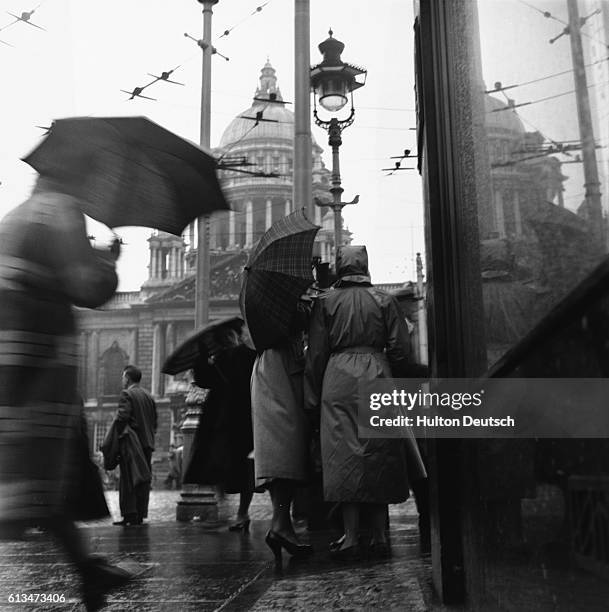 Pedestrians huddle beaneath umbrellas as they go about their business in Donegall Square, outside City Hall .