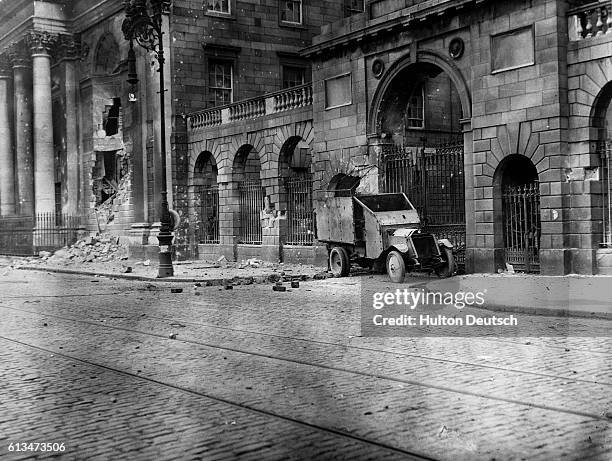 An armored car stands outside the gates of the Four Courts building in Dublin, damaged during its seizure by anti-treaty IRA members. Ireland, 1922.