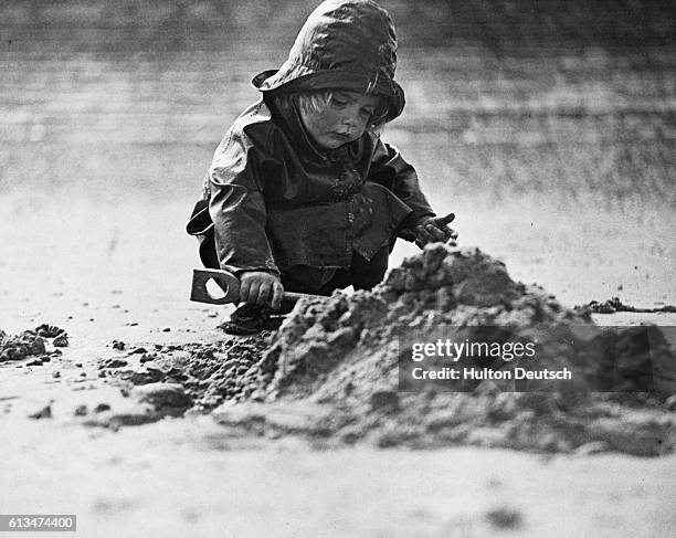 Year-old girl is undeterred by the rain as she plays on a beach in Kent.