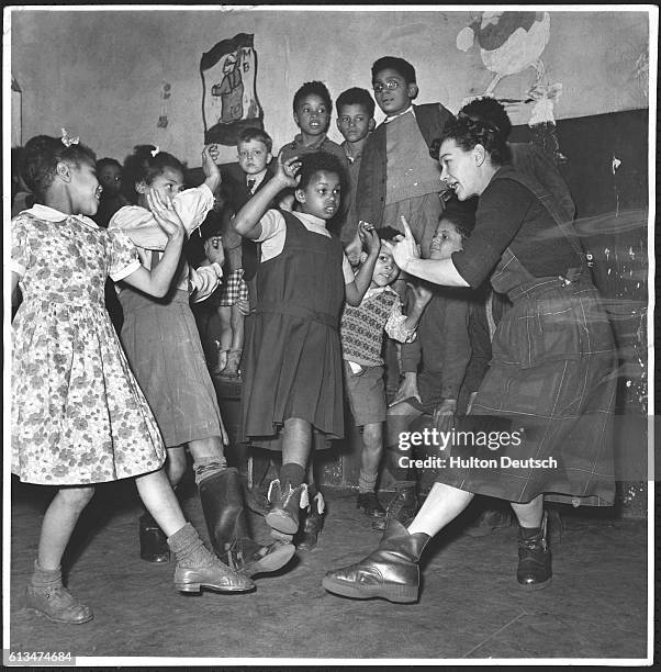 Young members of the Save the Children Fund, England's largest international children's organization, enjoy a lively dance at their club, doing the...