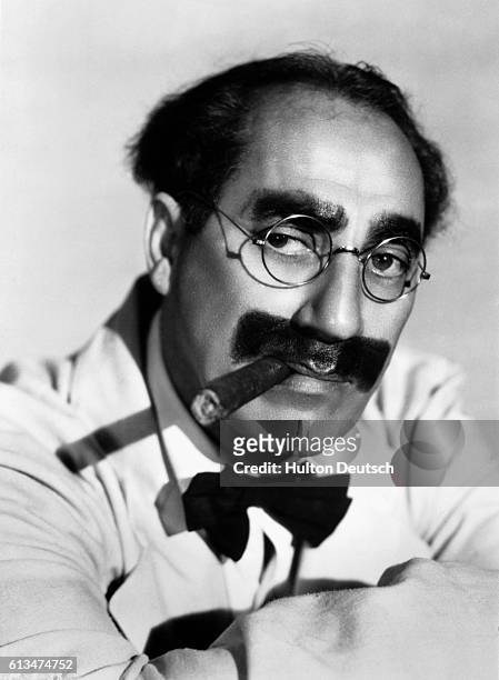 Comedian Groucho Marx, with his trademark cigar and greasepaint facial hair.