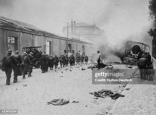 British soldiers march through a street in Dunkirk as it is heavily bombed in an attempt by the Germans to take the town before the evacuation of the...