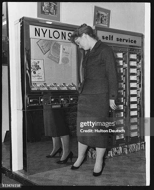 Sally Eves tries on a pair of nylon stockings bought from a machine at the first International Automatic Vending Machine Fair at the Royal...