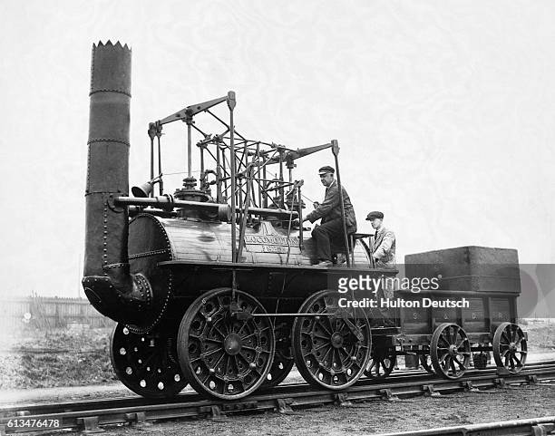 Two men drive one of the early steam locomotives invented by English engineer George Stephenson in the 1820s.