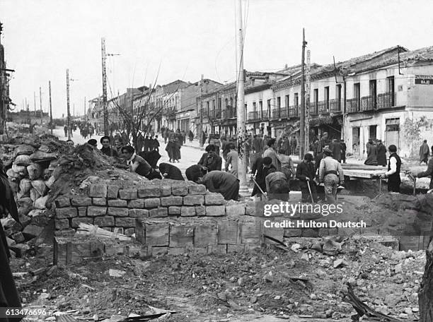 People knock down a barricade and gun emplacement, as life returns to normal after the end of the Spanish Civil War. | Location: Madrid, Spain.