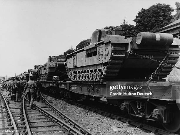 British Army tank crews make their way across a London, Midland and Scottish Railway siding to a train carrying Churchill tanks on route to an...