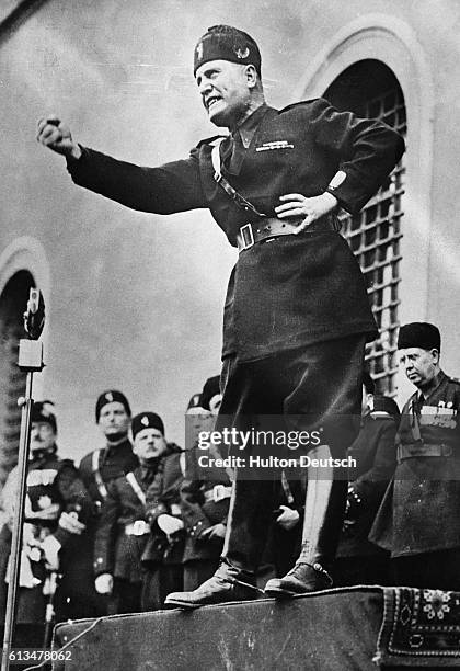 Benito Mussolini, "Il Duce," assumes a characteristic pose as he speaks to an audience in Italy in 1934. Mussolini was widely regarded as a hero and...