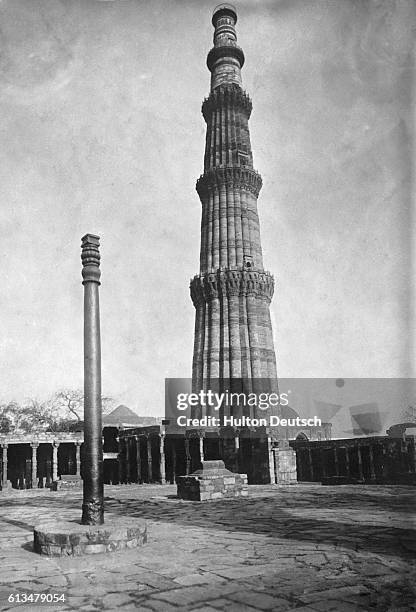 The tapered, sandstone and marble, Qutab Minar victory tower looms above a courtyard of the ruined 12th century Quwwat-ul-Islam Masjid mosque. In the...