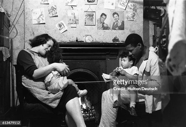 Mr. Siebert Mattison, a foundry worker, who left Jamaica in 1947, sits with his Welsh wife and their children, in their one-room, Birmingham home.
