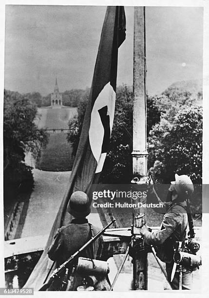 German soldiers raise the Nazi flag at the Royal Castle at Lacken after German troops invaded Belgium, 1940. | Location: Lacken, Belgium.