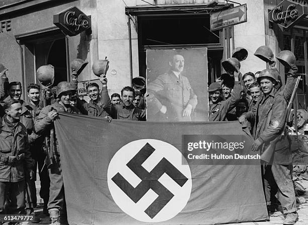 Soldiers of the 7th US division seen with a Nazi flag and a portrait of the Fuehrer. Saarbrucken, the capital of the Saar, falls without a battle to...