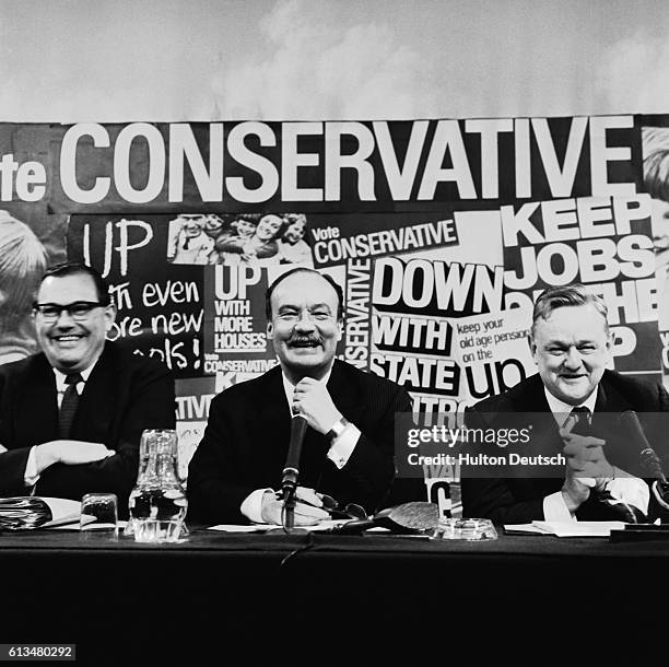 The British Conservative politicians Reginald Maudling, Lord Blakenham and Quintin Hogg sit in front of campaign posters for their party, during the...