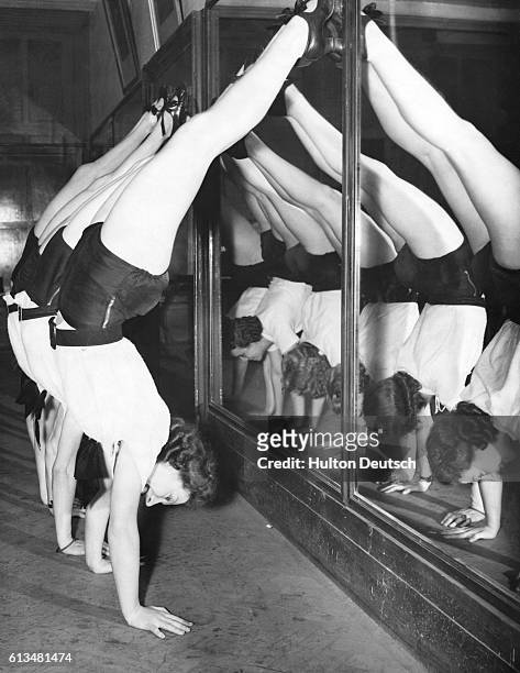 Chorus girls from the John Tiller troupe do handstands as part of their training for their role in the pantomime Red Riding Hood at the Royal Opera...