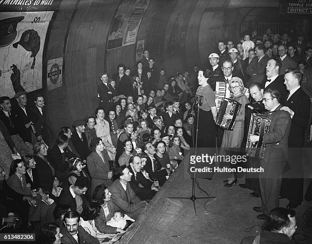 Members of the public watching a performance by the Entertainments National Service Association, as they shelter from bomb raids in Aldwych Tube...