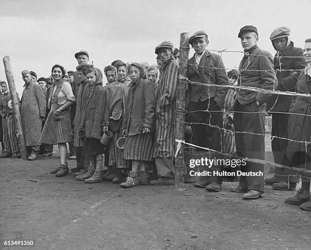 Hungry internees wait eagerly at the cook house gate for their ration of potato soup, in the German prison camp at Belsen, Germany, where the German...