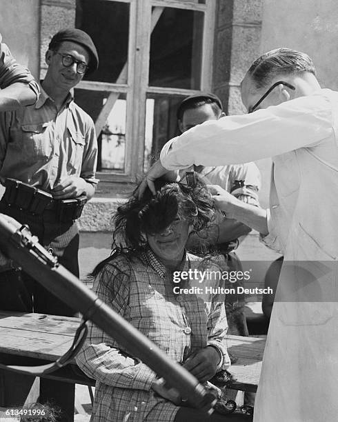 Woman has her head shaved by a barber. She may have cooperated with enemy German soldiers, or had sexual relations with the enemy force, or exchanged...