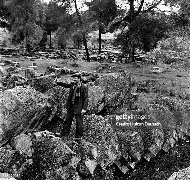 Man points to the spot where Phidias' statue of Zeus once stood, within the grounds of the largest temple, at the ancient Greek sanctuary of Olympia....