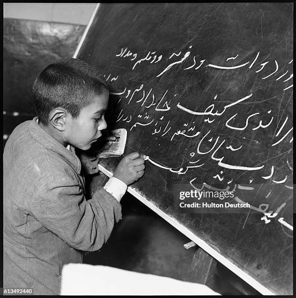 Male student writes using his native Persian language on a blackboard in a school for worker's children in Abaogan, Iran. | Location: Abaogan, Iran.