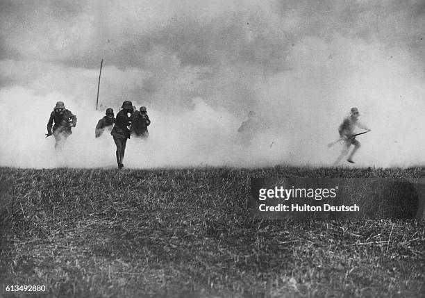 German storm troopers, led by an officer, emerge from a thick cloud of phosgene poison gas laid by German forces as they attack British trench lines....