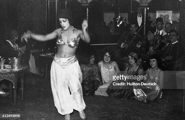 An audience watches a belly dancer perform a belly dance.