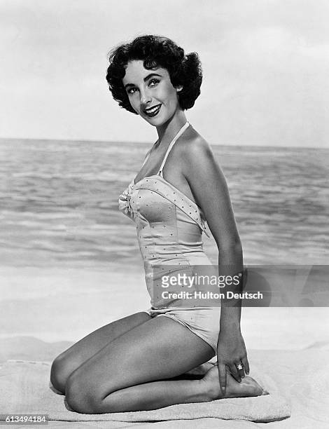 Elizabeth Taylor poses in swimwear in a beach scene.