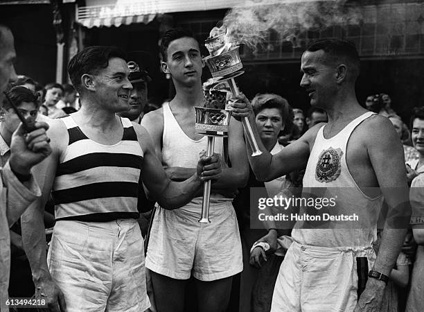 Lighting flame from Olympic torch carried by N.J.Bignal.