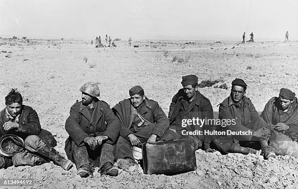 Six Italian soldiers who were captured by American troops, rest on the north African desert.