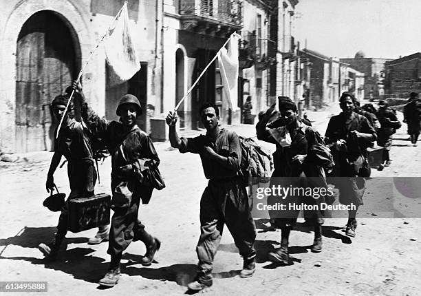 Italian soldiers enter a town near Messina in Sicily and wave white flags to signal their surrender to the Allies during World War II.