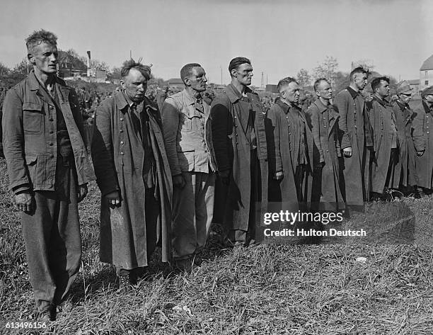 Weariness and defeat etch the faces of a line of SS troopers captured by Allied soldiers. The men were identified as some of those who killed Allied...