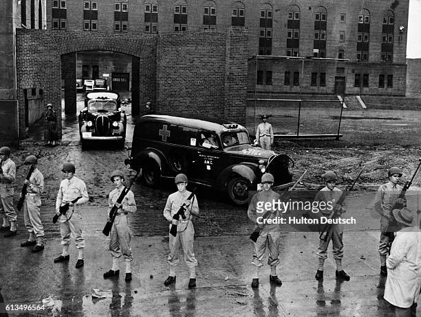 Armed soldiers guard the ambulances that are carrying the bodies of six executed Nazi saboteurs who plotted against the United States away from...