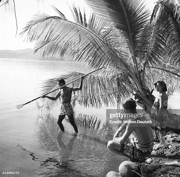 Spear fisherman studies the waters of a lagoon in Tahiti, getting ready to catch some fish.