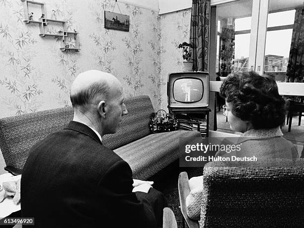 Bank manager and his wife relax at home, in front of their television.