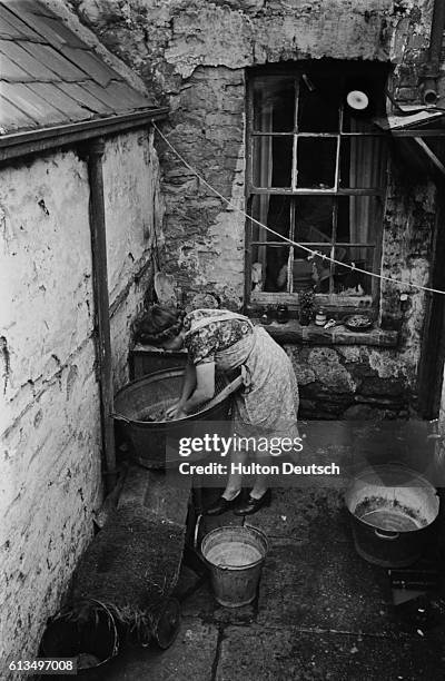 Housewife scrubs laundry in a washtub in the backyard of her Swansea home.