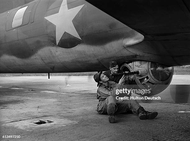 Rudolf Portong of the USA shows a Royal Air Force ground crew worker how the gun attached to the underside of a Flying Fortress works, ca. 1942.